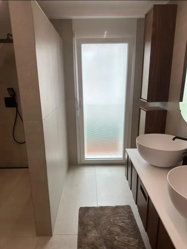 Badezimmer in Schöftland mit Dusche, Waschtisch und Plattenbelägen