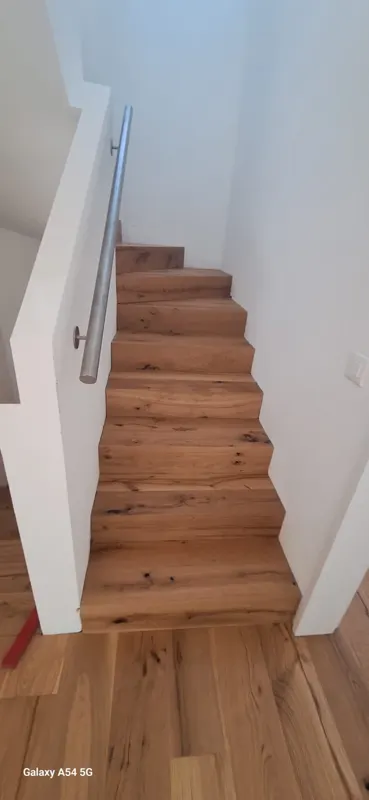 Holztreppe mit weisser Wand und Handlauf in Sursee