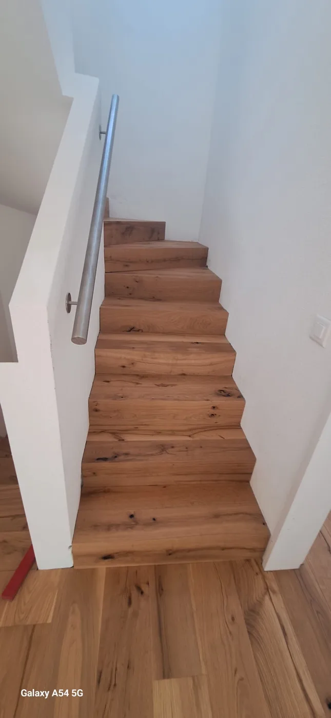 Holztreppe mit weisser Wand und Handlauf in Sursee